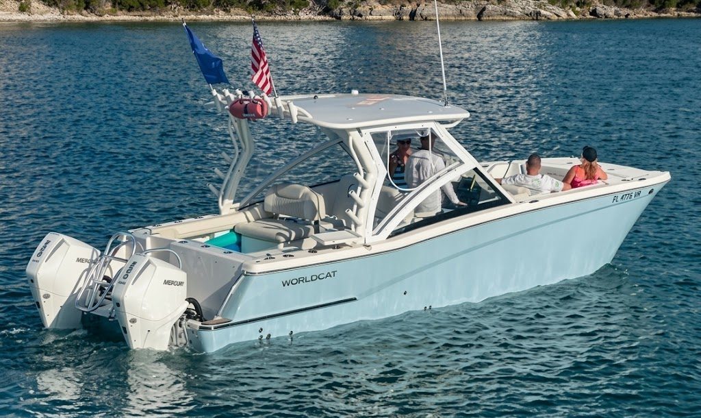A motorboat with two people on open water near a rocky shore.